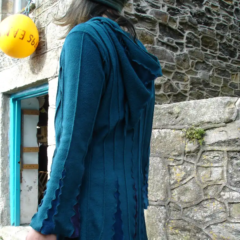 Hood and back/sleeve detail on a Feeline cardigan/jacket, in blue. modelled outside Salt Cellar Workshops, Porthleven, Cornwall