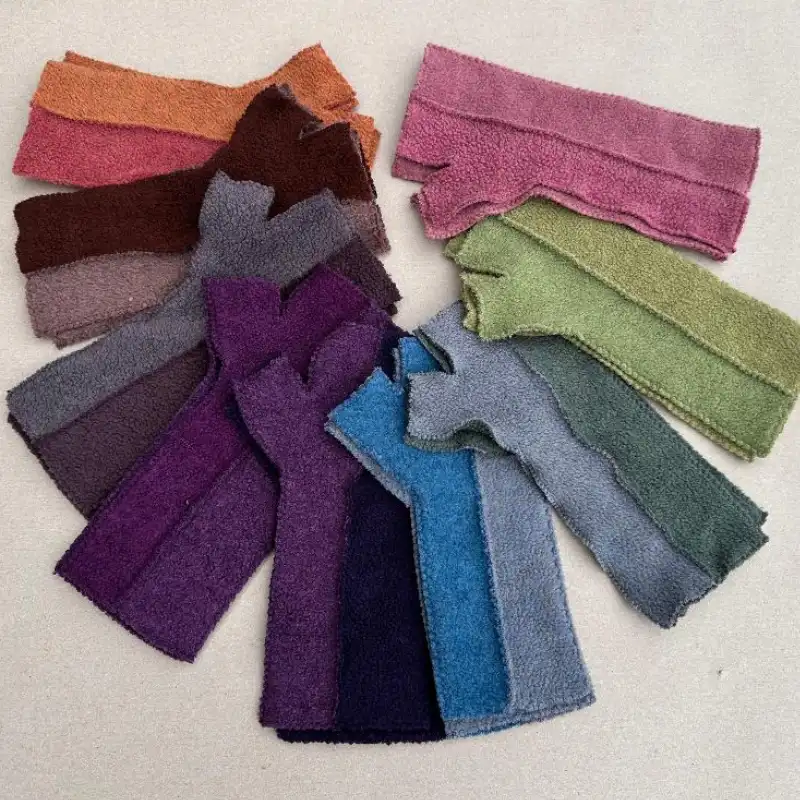 9 pairs of Feeline Clothing mittens laid out in a semi circle, in a range of many colours