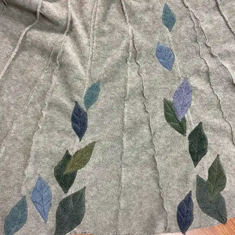 appliquéd leaves in blue, turquoise and grey, on a soft fleece zip opening top.