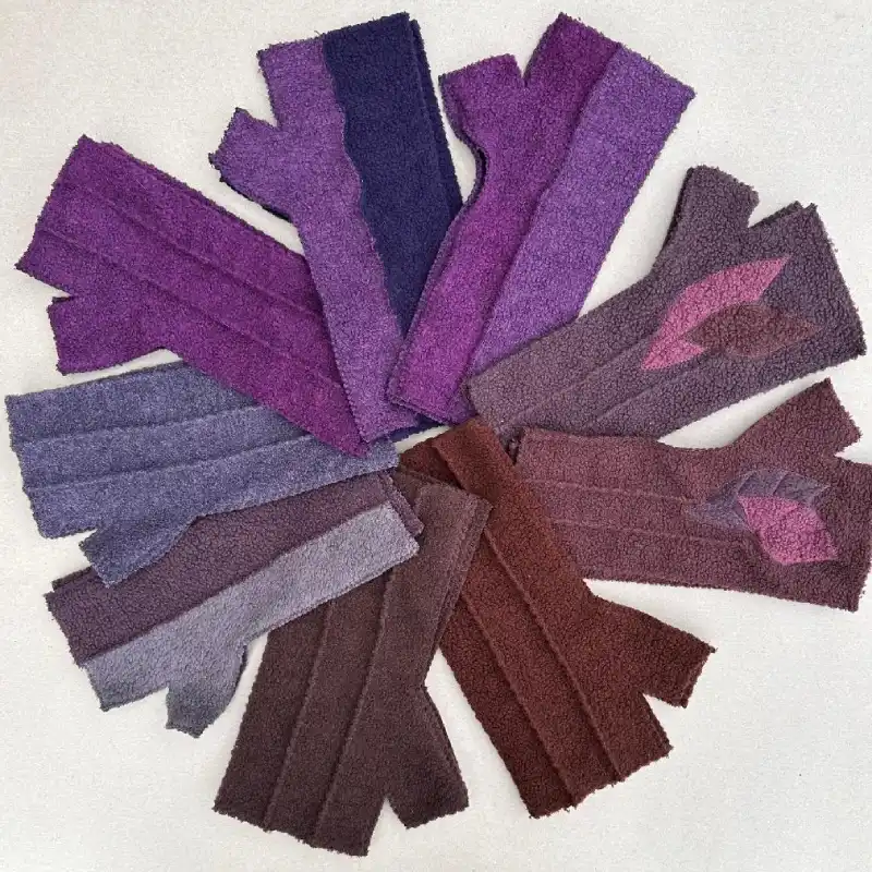 9 pairs of Feeline Clothing mittens showing 3 of the available styles, in various shades of violet, purple, grey and brown, laid out in a circle.