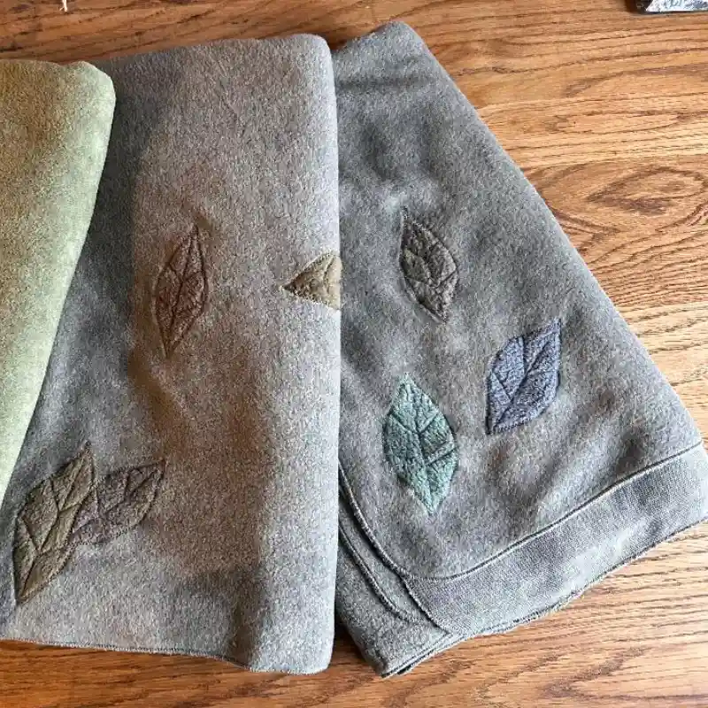 some Feeline Clothing scarves/shawls, with appliquéd leaves in soft muted colours. On sale in Salt Cellar Workshops, Porthleven, Cornwall