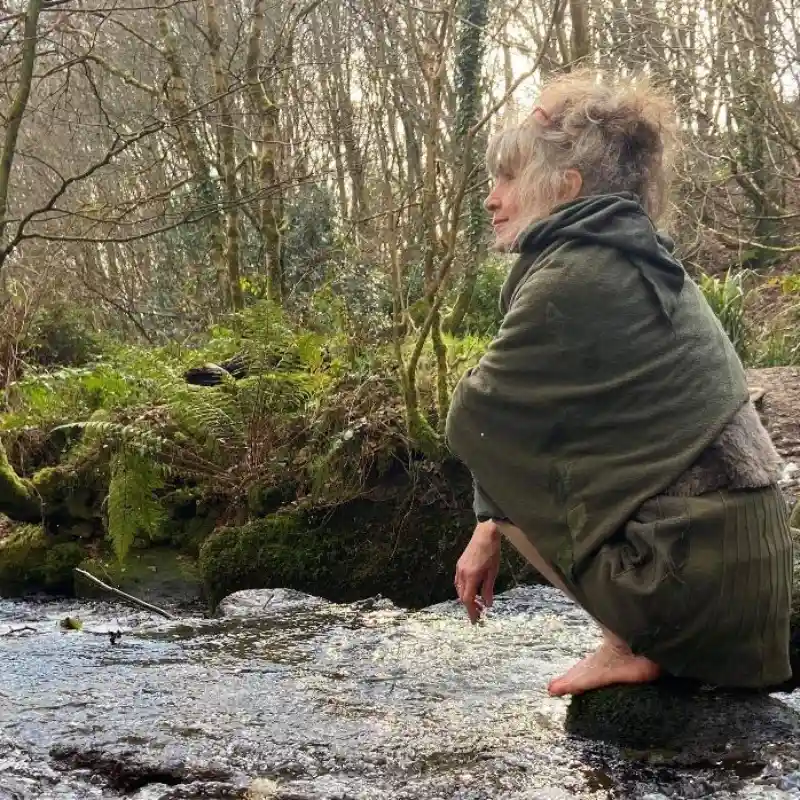 a Feeline Clothing scarf being modelled sitting on a rock in the middle of a stream