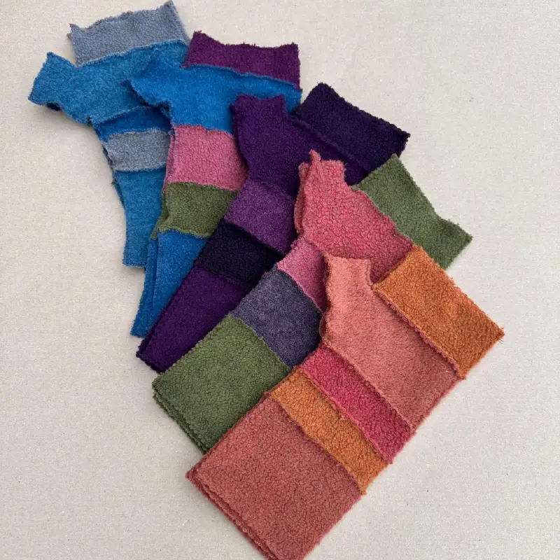 a cascade of striped Feeline Clothing mittens in many colours. orange, pink, green, purple, blue, and grey.