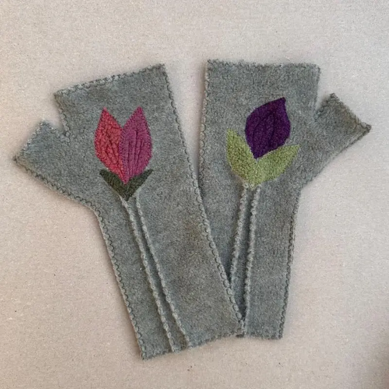 a pair of Feeline Clothing petal mittens, one hand with pink and coral petals and green leaves, the other hand a dark purple petal and lighter green leaves, on a sage overall colour.